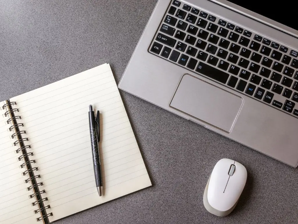 Open notebook, pen, and laptop, representing copywriting