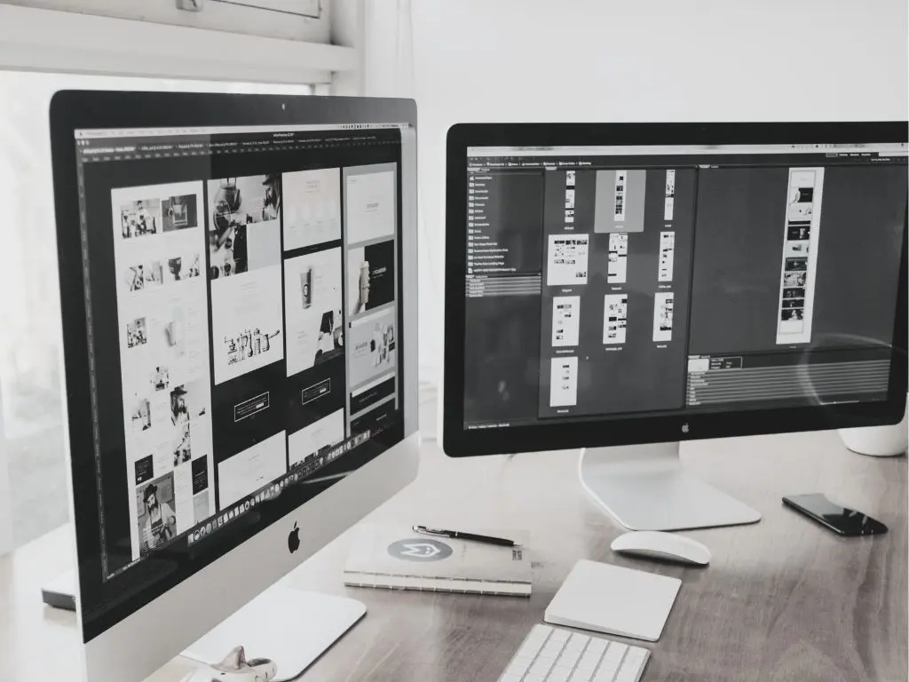 Two monitors showing website layouts, representing web design